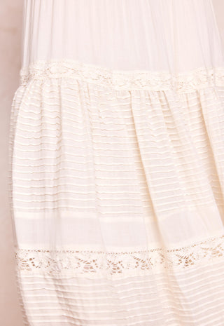 Close-up of a cream-colored sheer mesh and textured fabric garment with delicate lace trim details.