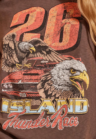Close-up of a brown graphic t-shirt featuring a distressed red and orange '26' number, a bald eagle, a red muscle car, and 'ISLAND Thunder Race' text.