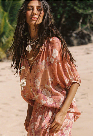 A woman on a sandy beach wearing a loose