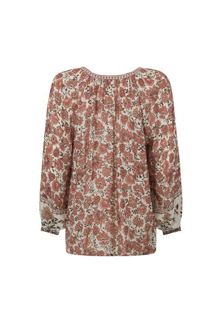A long-sleeve blouse with a dense floral and paisley print in dusty rose, rust red, and beige, featuring a gathered round neckline and a loose silhouette.