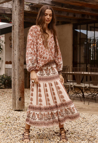 A woman wearing a bohemian-style two-piece dress set with a rust brown and cream floral print