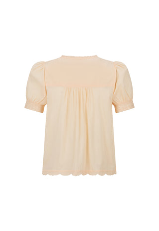 A light peach-colored blouse with short puff sleeves, a gathered smocked bodice, and a scalloped hem, shown against a plain white background.