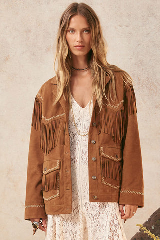 Woman wearing a brown fringed jacket against a neutral background
